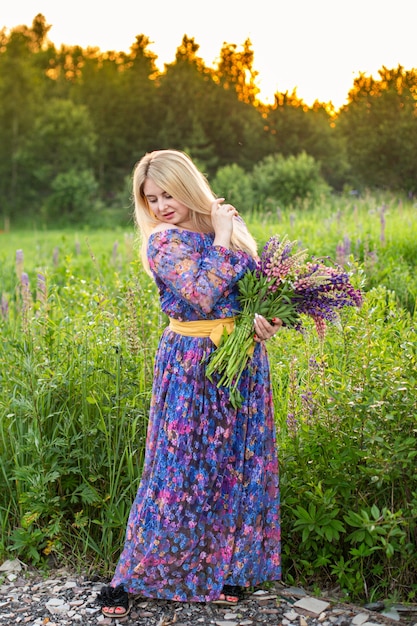 Portrait of a girl in a blooming field in the sun at sunset