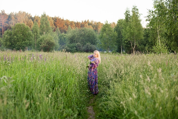 Portrait of a girl in a blooming field in the sun at sunset