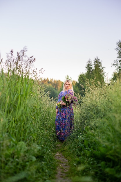 Portrait of a girl in a blooming field in the sun at sunset