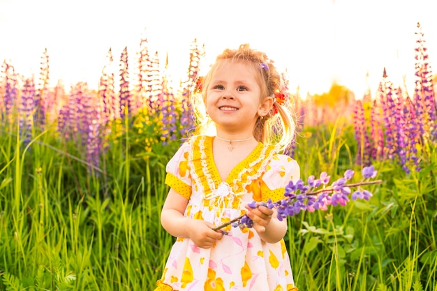 Portrait of a girl in a blooming field in the sun at sunset