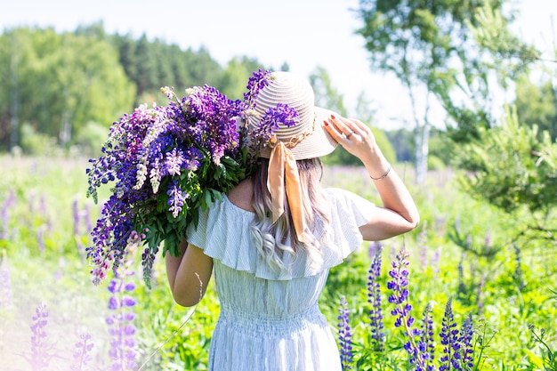 Portrait of a girl in a blooming field in the sun at sunset