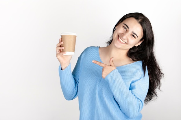 浅い背景のコーヒーを飲む青いジャケットの女の子の肖像画