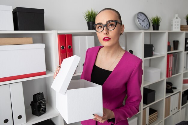 Portrait of a girl in business style who is looking for documents in a white box