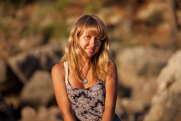 Portrait of a girl by the sea. Sunset sun and rocky rocks