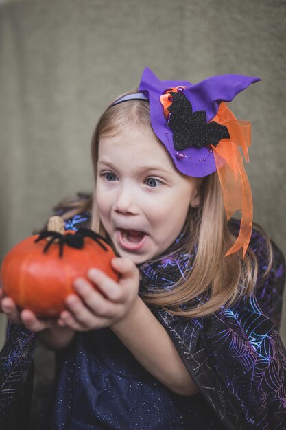 Foto ritratto di una ragazza in abiti da carnevale per halloween con una zucca