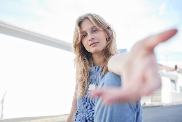 Portrait of girl in the city with hand reaching forward sitting in the street Student education and young woman in college with hands out in urban road Motivation encourage and freedom in youth