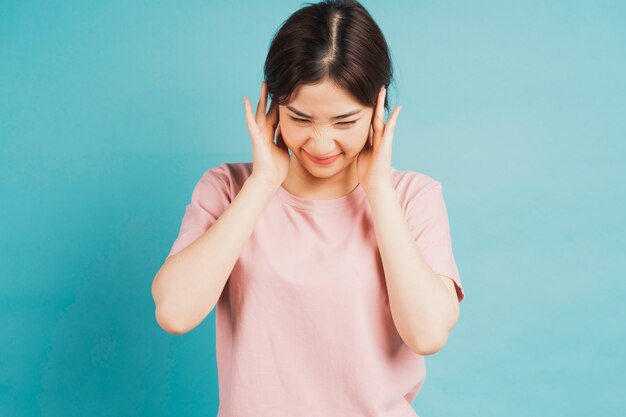 Portrait of girl coning ears and feeling discomfort on blue