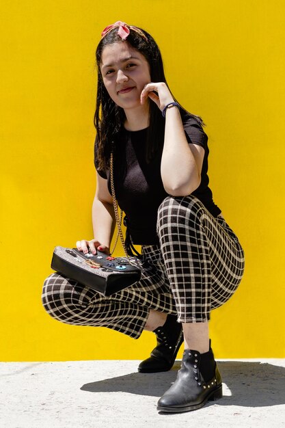 Portrait of girl crouching against yellow wall