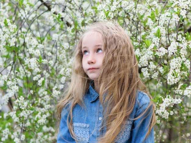 Portrait of a girl in a denim shirt with her hair down in a cherry Park