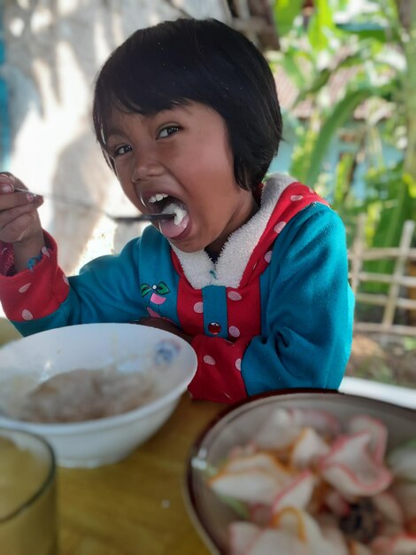 Photo portrait of girl eating food at home