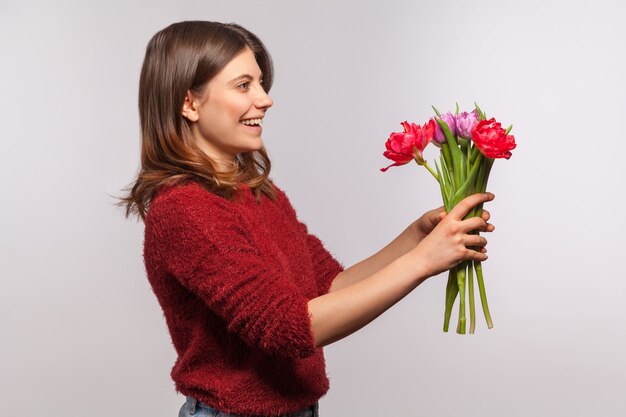 Ritratto di ragazza che dà bouquet di fiori e sorride eccitato. congratulazioni per le vacanze di primavera