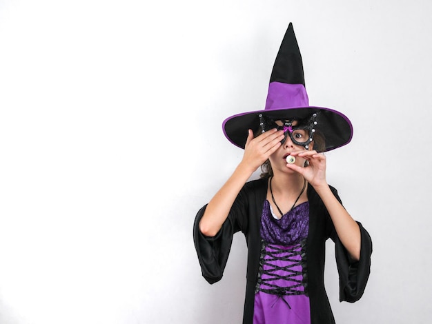 Portrait of a girl in a Halloween witch costume a hat holding candy and closing her eye