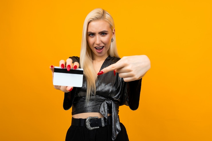 Photo portrait of a girl holding a card for shopping on a yellow background