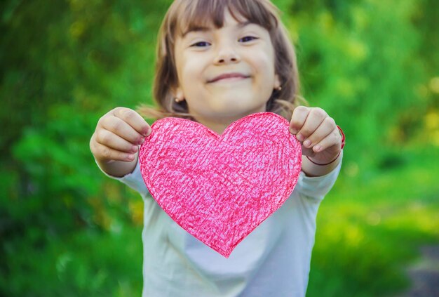 Photo portrait of girl holding heart shape