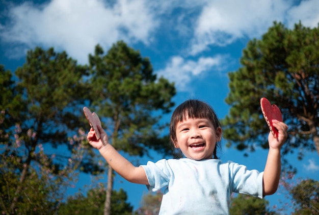 Portrait of girl holding heart shapes against trees