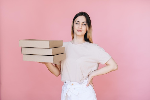 Portrait of a girl holding pizza boxes in her hands and looking at the camera hand on her hip