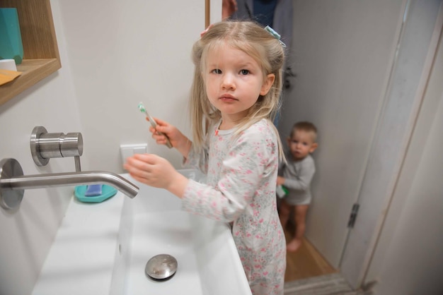 Foto ritratto di una ragazza che tiene uno spazzolino da denti da un bambino in bagno a casa