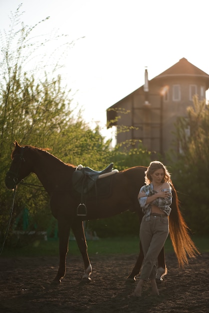 Портрет девушки в клетчатой рубашке с черной лошадью на конной ферме.