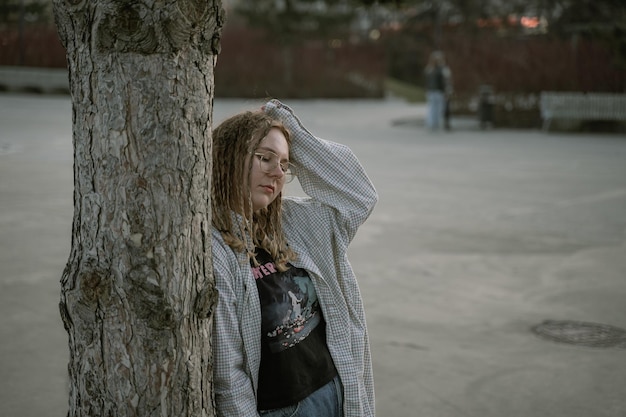 Photo portrait of a girl leaning against a tree