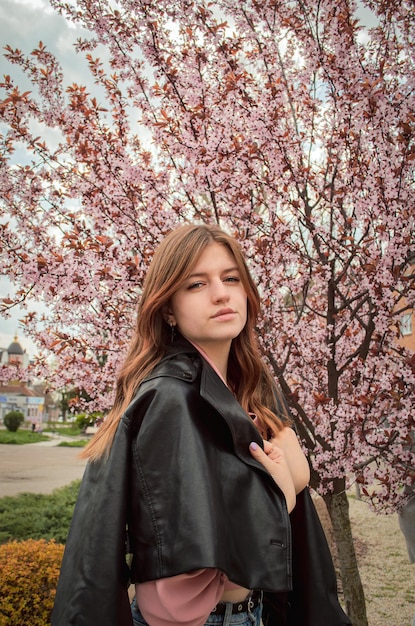 Portrait of a girl in a leather jacket in spring flowers