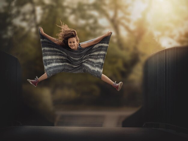 Photo portrait of girl levitating over footbridge