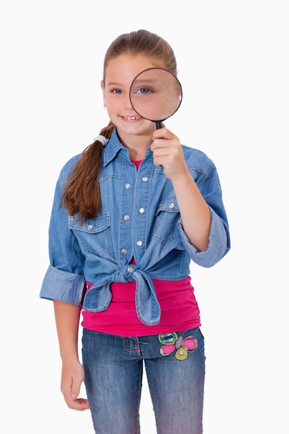 Photo portrait of a girl looking through a magnifying glass