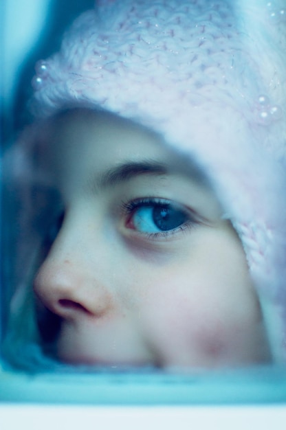 Portrait of girl looking through window