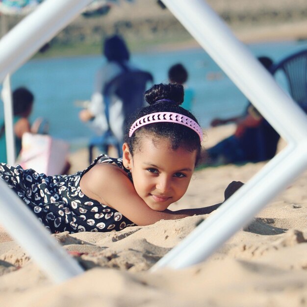 Photo portrait of girl lying on sand at beach