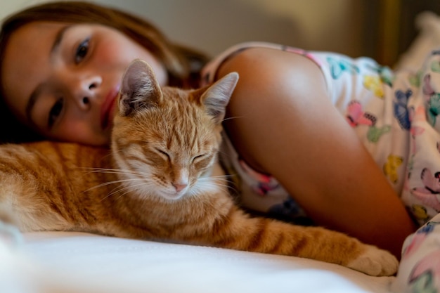 portrait of girl lying with cat on bed at home