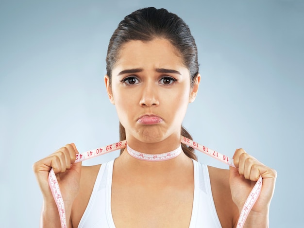 portrait girl and measuring tape on neck for mental health eating disorder and body dysmorphia female person anxiety and weight loss with negative emotion stress or unhappy on studio background