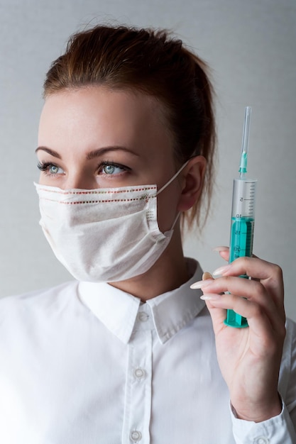 Portrait of a girl in a medical mask Holding a syringe in her hand Close upxA