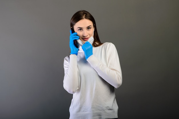 Портрет девушки в медицинской маске разговаривает по телефону