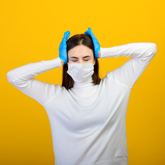 Portrait of a girl in a medical mask with hands on her head