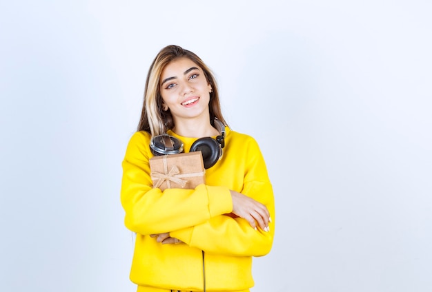 Portrait of a girl model holding a paper box with bow isolated over white wall