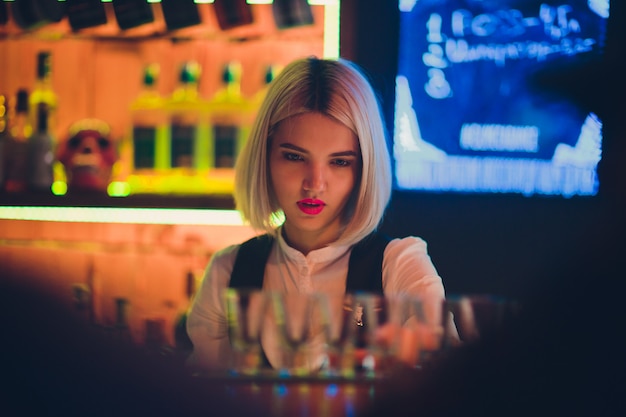 Portrait of a girl in a night bar, behind the counter.