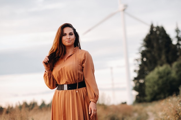 Portrait of a Girl in an orange long dress with long hair in nature in the evening