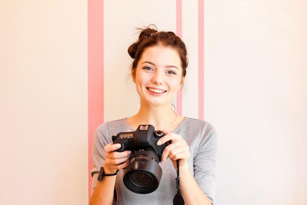 Portrait of girl photographer smiling and holding her camera