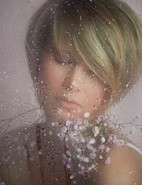 Portrait of a girl on a pink background with flowers Tenderness and feminine The sphere of beauty and women's health Short haircut blonde hair