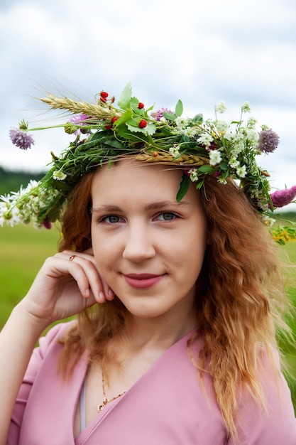 Ritratto di ragazza in abito rosa con corona di fiori di campo