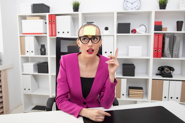 Photo portrait of a girl in a pink jacket with a sticker on her forehead. the process of creating ideas at work