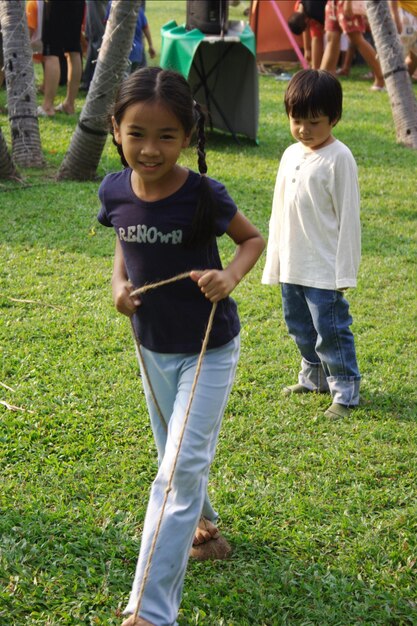 Photo portrait of girl playing with string at park