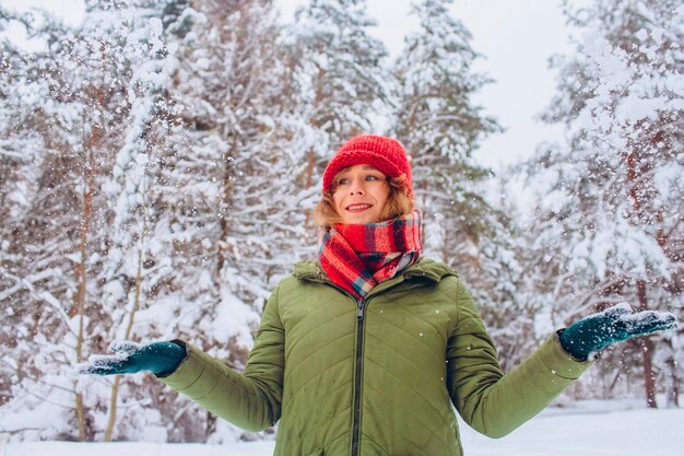 Portrait of a girl in a red hat and scarf in the winter forest