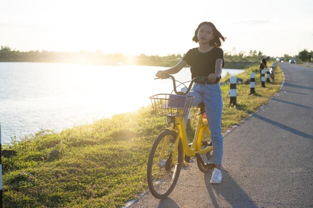 Photo portrait of girl riding bicycle on road by lake against sky