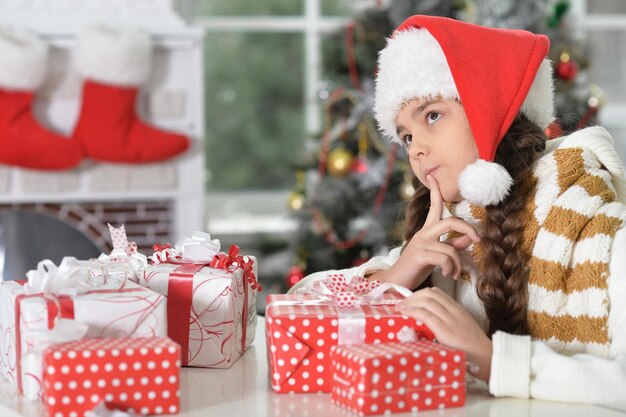 Portrait of girl in Santa hat with gifts