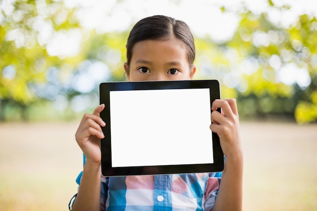 Photo portrait of girl showing digital tablet in park