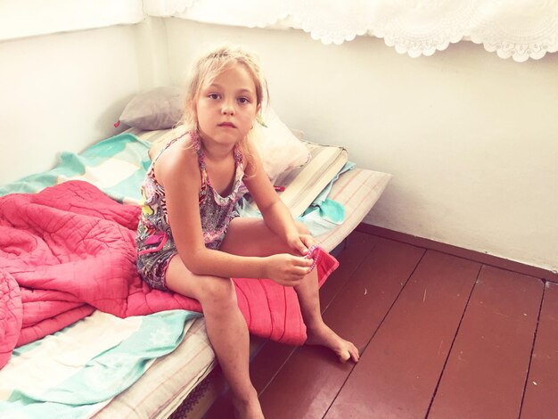 Photo portrait of girl sitting on bed at home