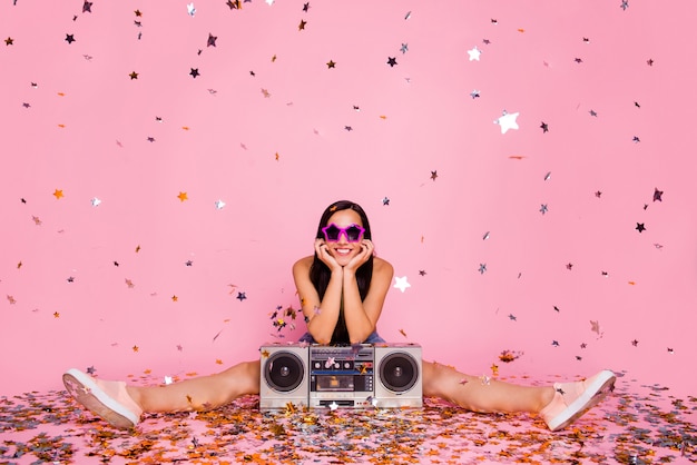 Портрет девушки, сидящей на полу, бумбокс, ожидание падения конфетти, изолированная розовая стена
