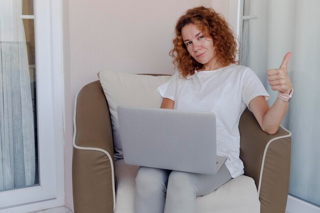 Portrait of a girl sitting on sofa and working at a laptop High quality photo