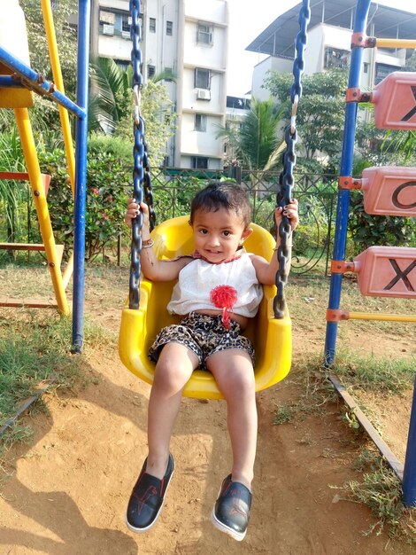 Portrait of girl sitting on swing in playground