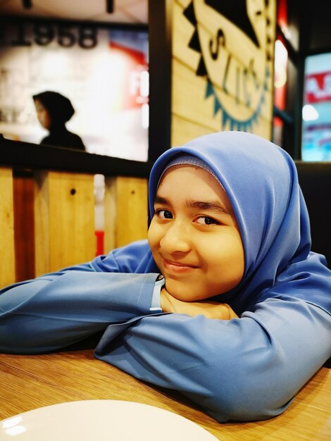 Photo portrait of girl sitting on table